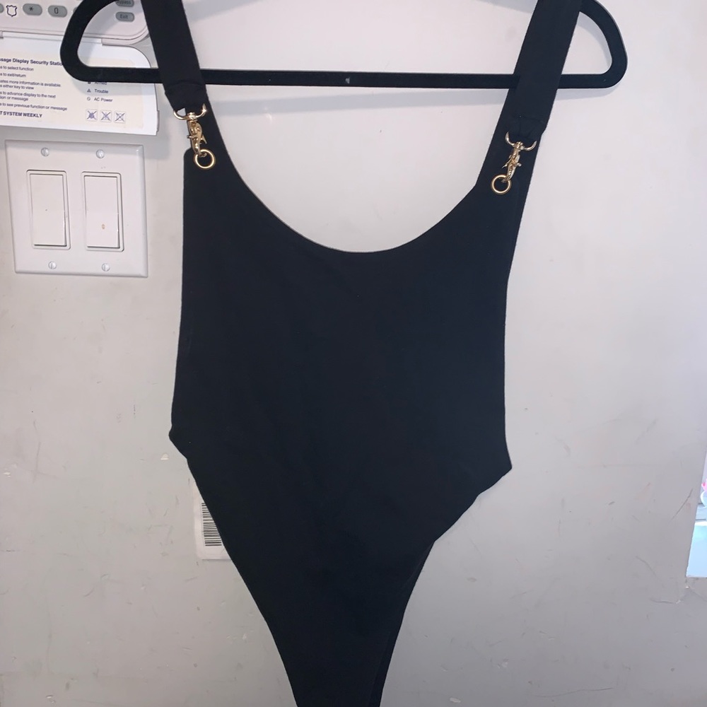 Black bodysuit with snaps. Very high sides on top and bottom. Chain link strap.